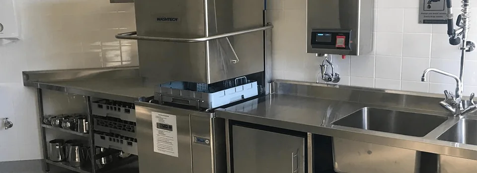 Commercial kitchen with a stainless pass-through dishwasher and sinks